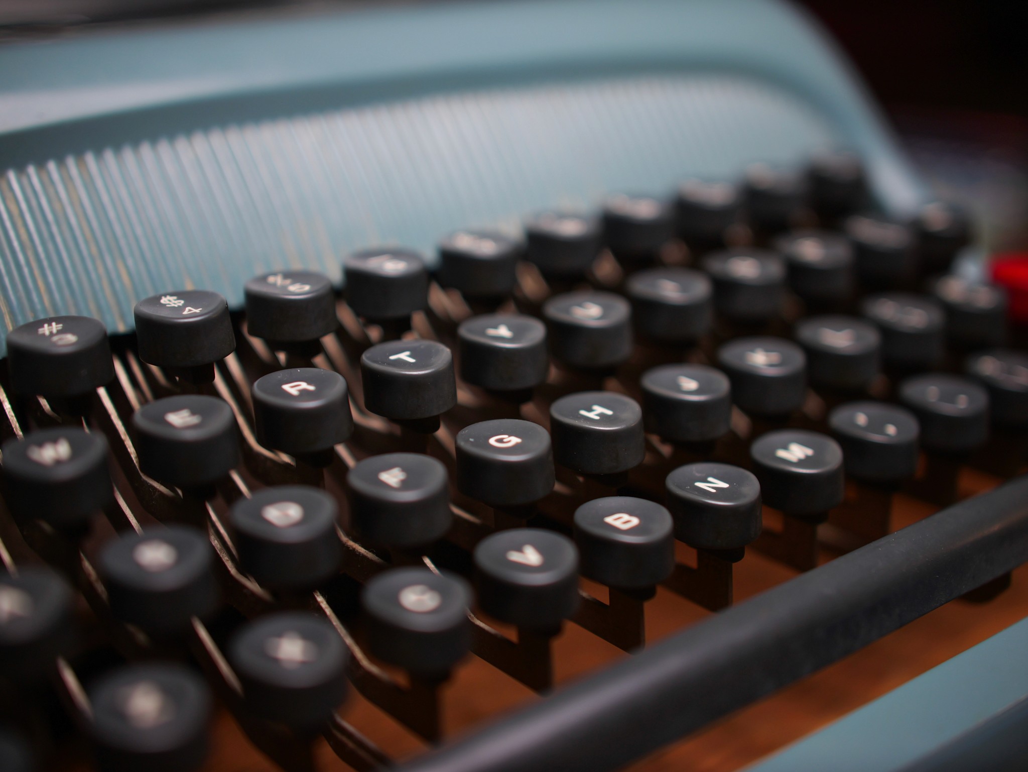 Vineyard rows under leafy foreground frame a Tuscan villa on a misty hill