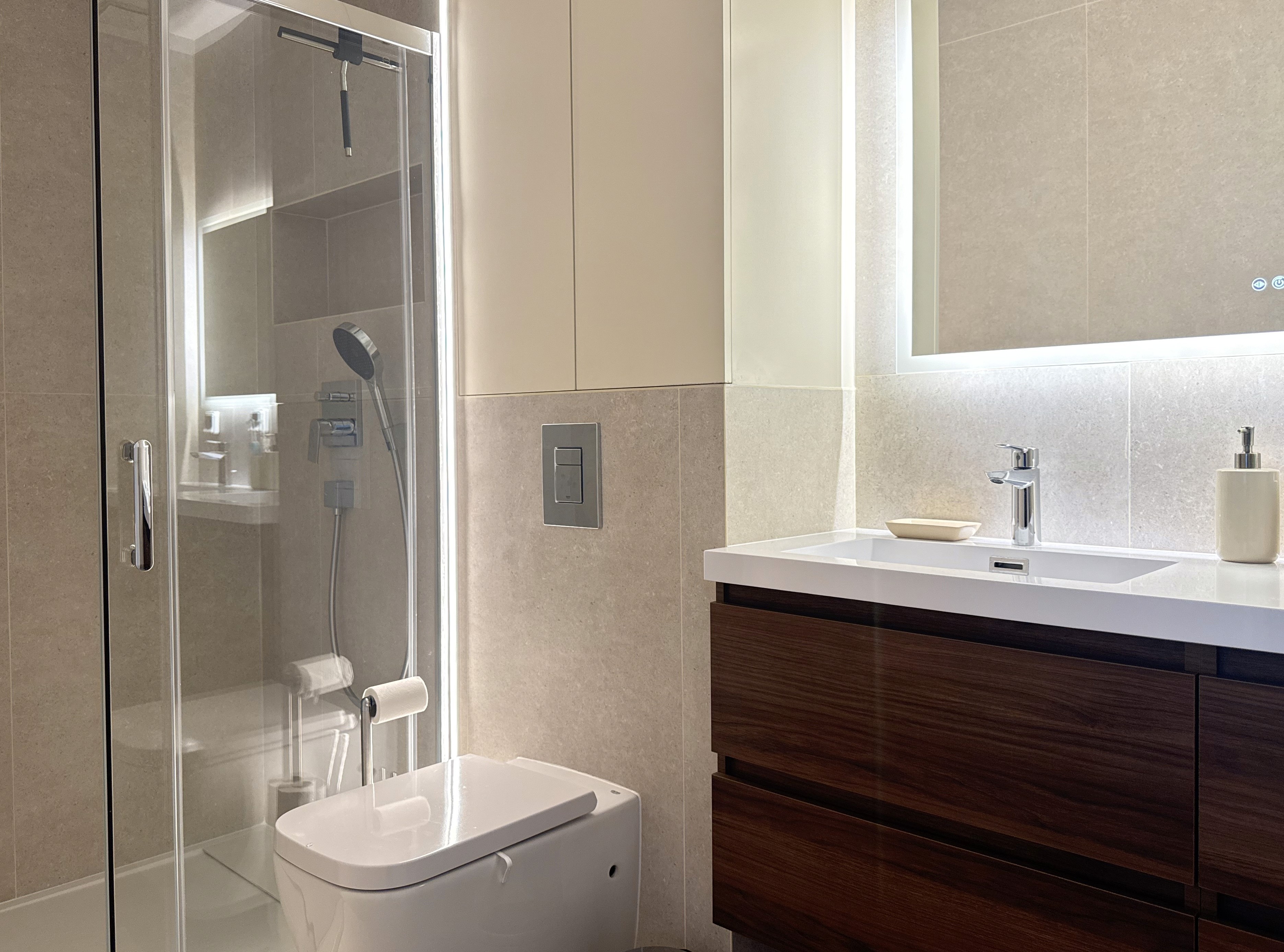 Vue de la douche à l'italienne et du second miroir rétro-éclairé, soulignant le travail sur l'éclairage d'ambiance de la salle de bain.