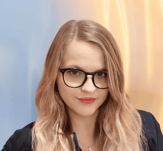 Maria Ksenia Witte, Expertin für Förderungen als strategischer Hebel, Portrait einer Frau mit langen blonden Haaren und Brille im Business-Outfit.