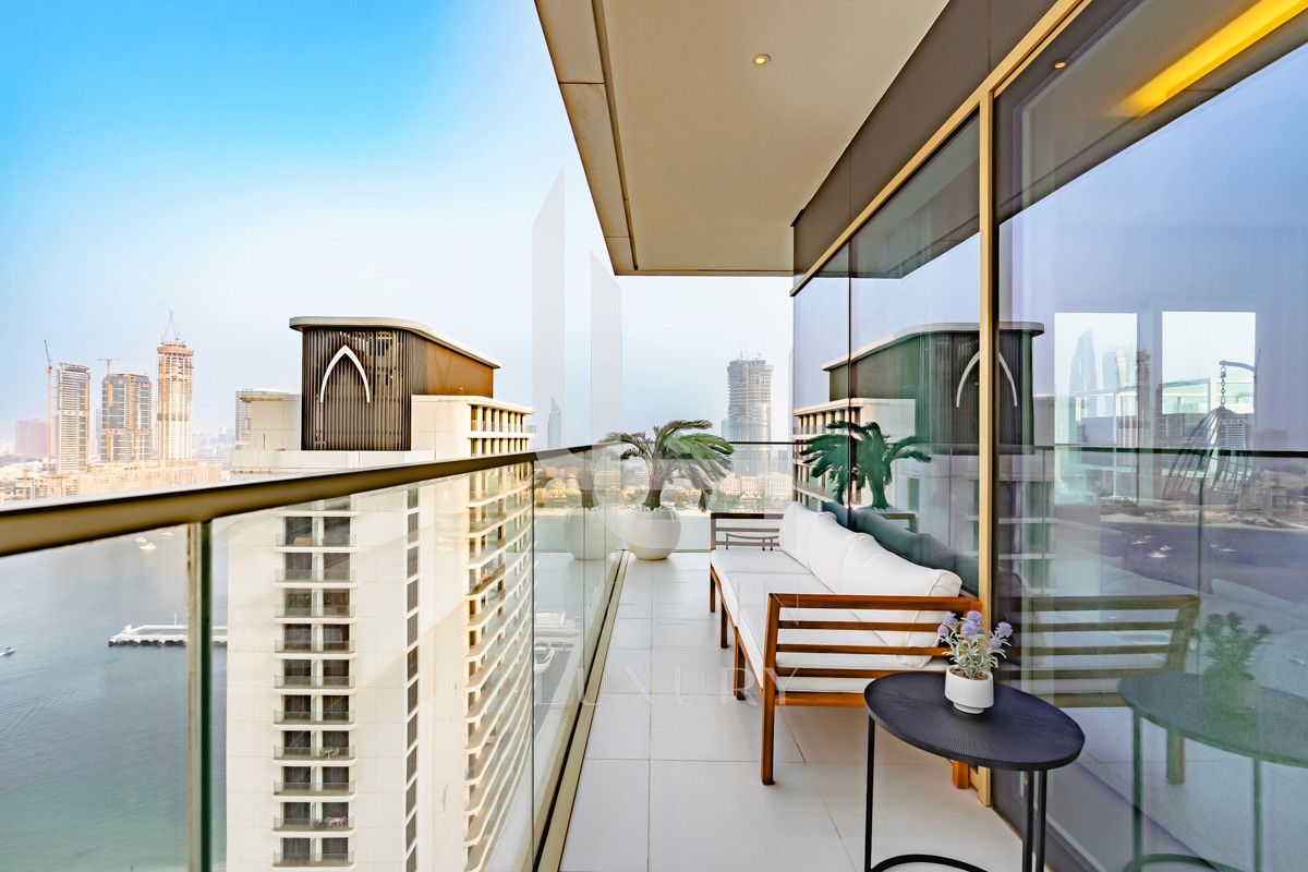 Die Küstenansicht von EMAAR Beachfront zeigt beeindruckende Hochhäuser, die sich entlang der Küste von Dubai erstrecken, während im Hintergrund die Skyline der Stadt zu sehen ist. Diese moderne Metropole bietet zahlreiche Fortbewegungsmöglichkeiten, darunter das Dubai Metro-System und Wassertaxis, die die Erkundung der Umgebung erleichtern.