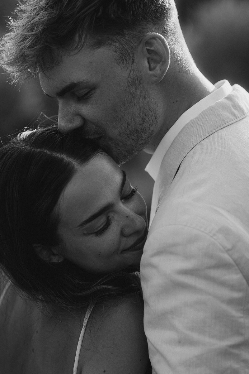 wedding couple black and white closeup of groom kissing bride on hair tuscany italy