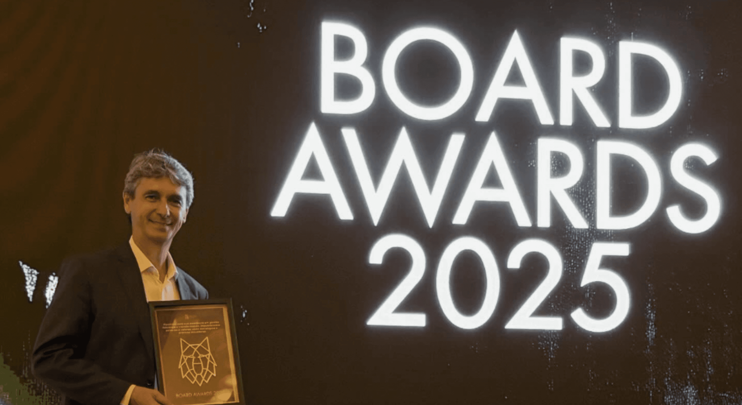 Ladmir Carvalho segurando prêmio em frente ao letreiro do Board Awards 2025