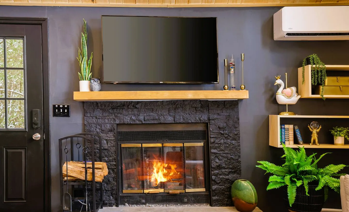 Wood-burning fireplace with black stone surround and TV above at Get Lucky On Lupine