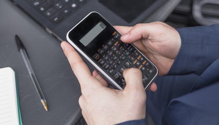 Homem fazendo calculos em pequena calculadora
