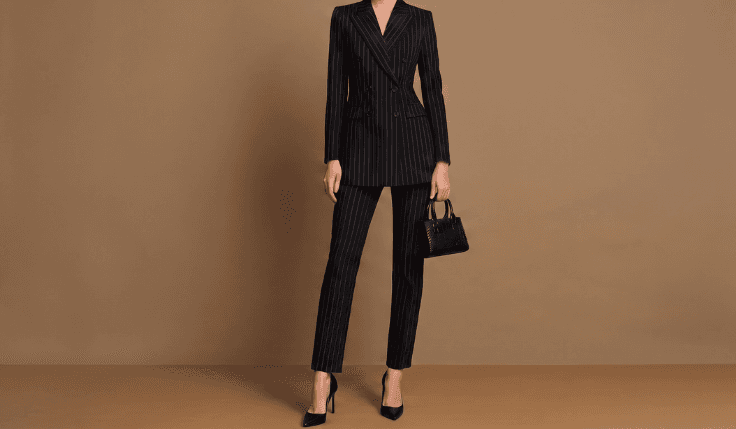 Woman wearing a black pinstripe double-breasted suit with a structured masculine silhouette