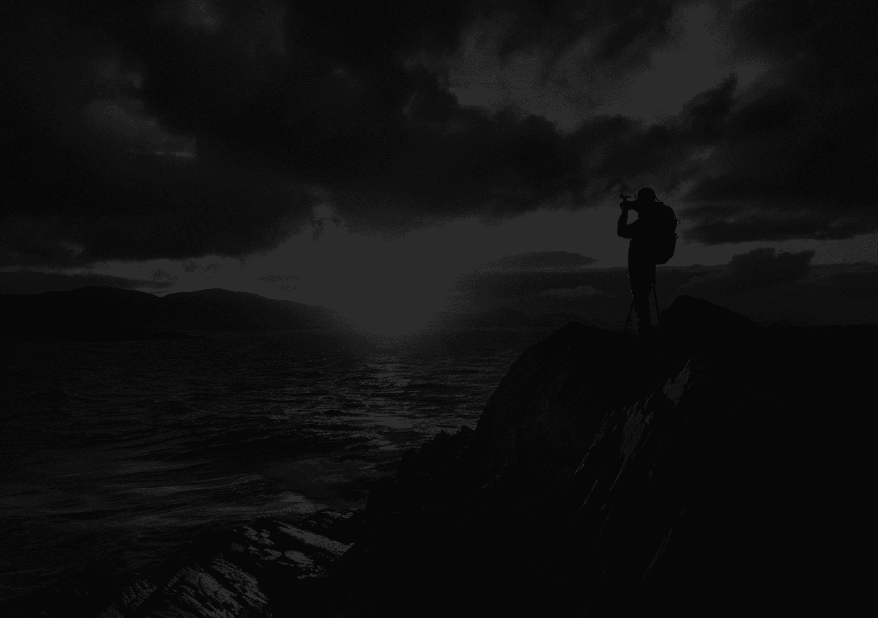 An image of a photographer at the end of a cliff taking a shot