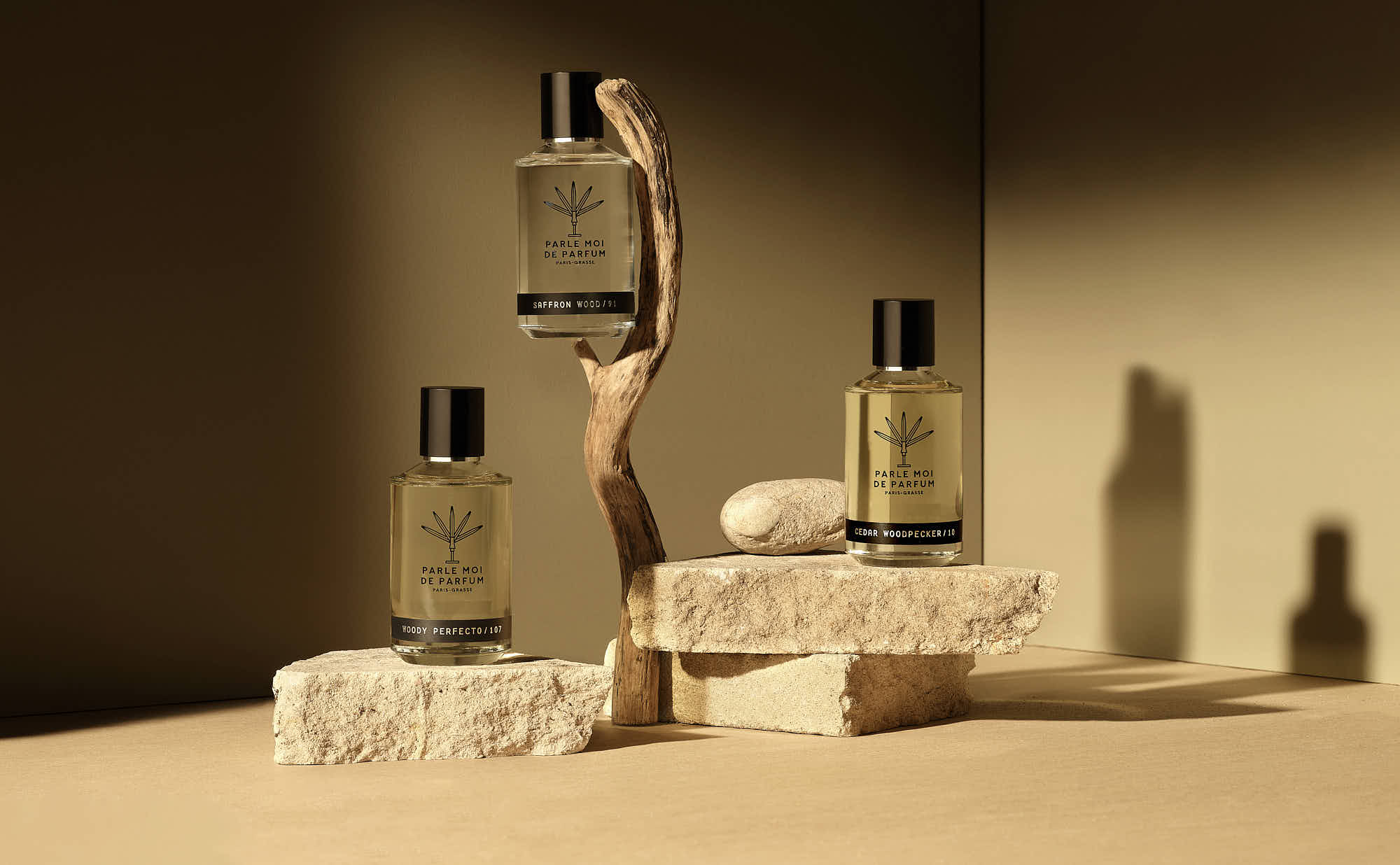 A minimalist display of perfume products on a wooden surface against a soft, neutral background.