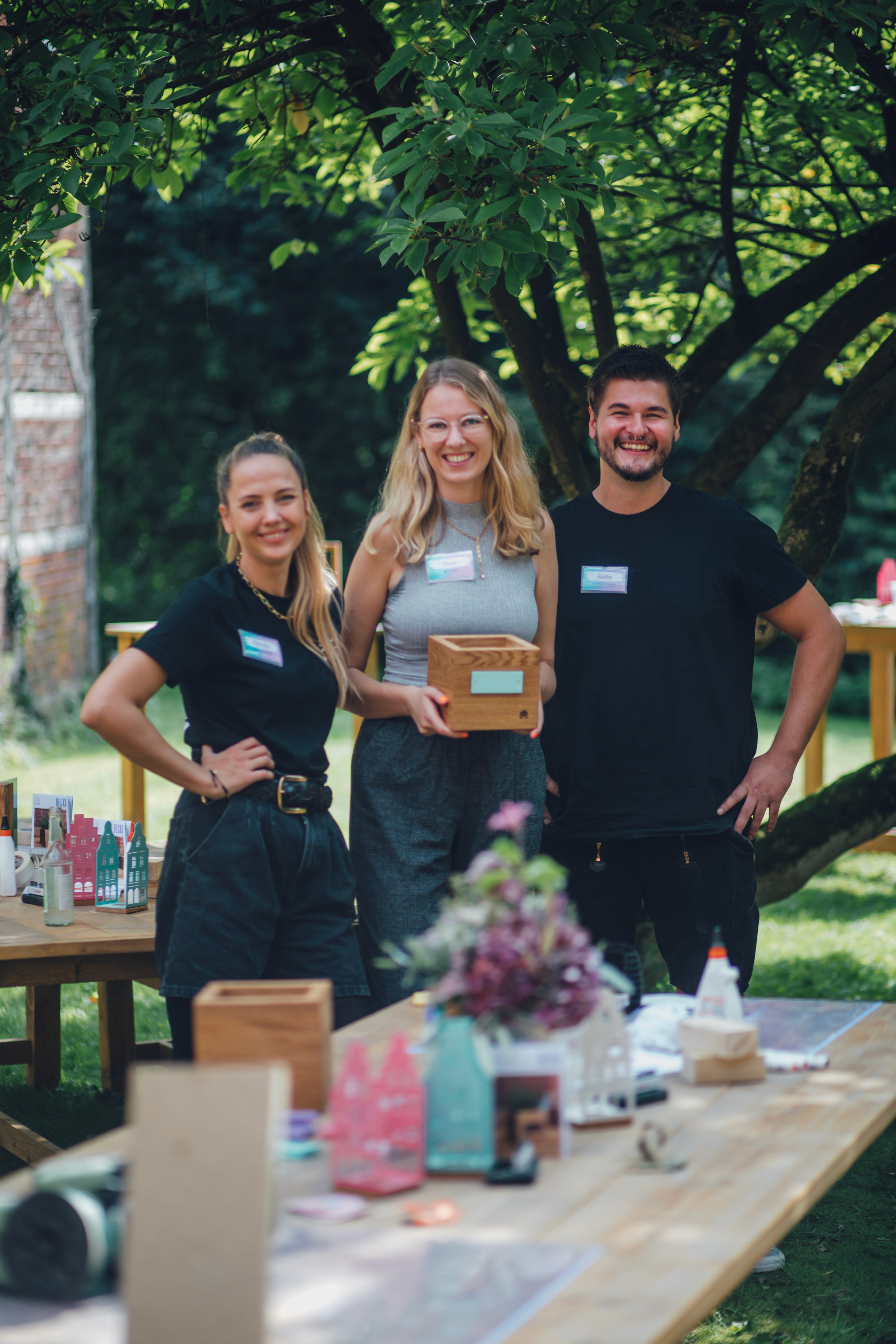 Die Workshopleiter:innen von Kawentsmann posieren mit einer Creatorin, die ihr handgemachtes DIY Ergebniss präsentiert.