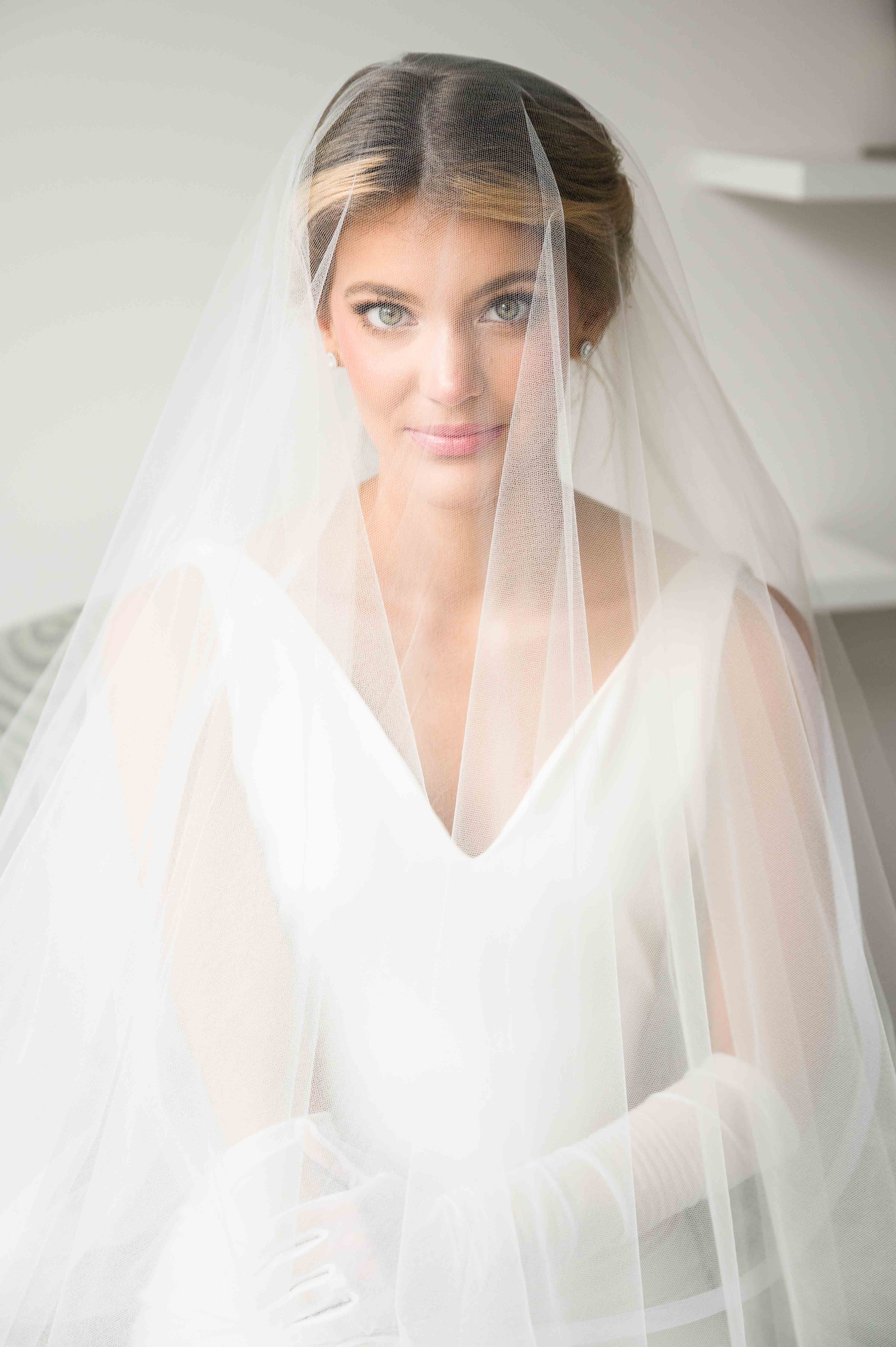 Portrait of bride under her veil looking directly at the camera.