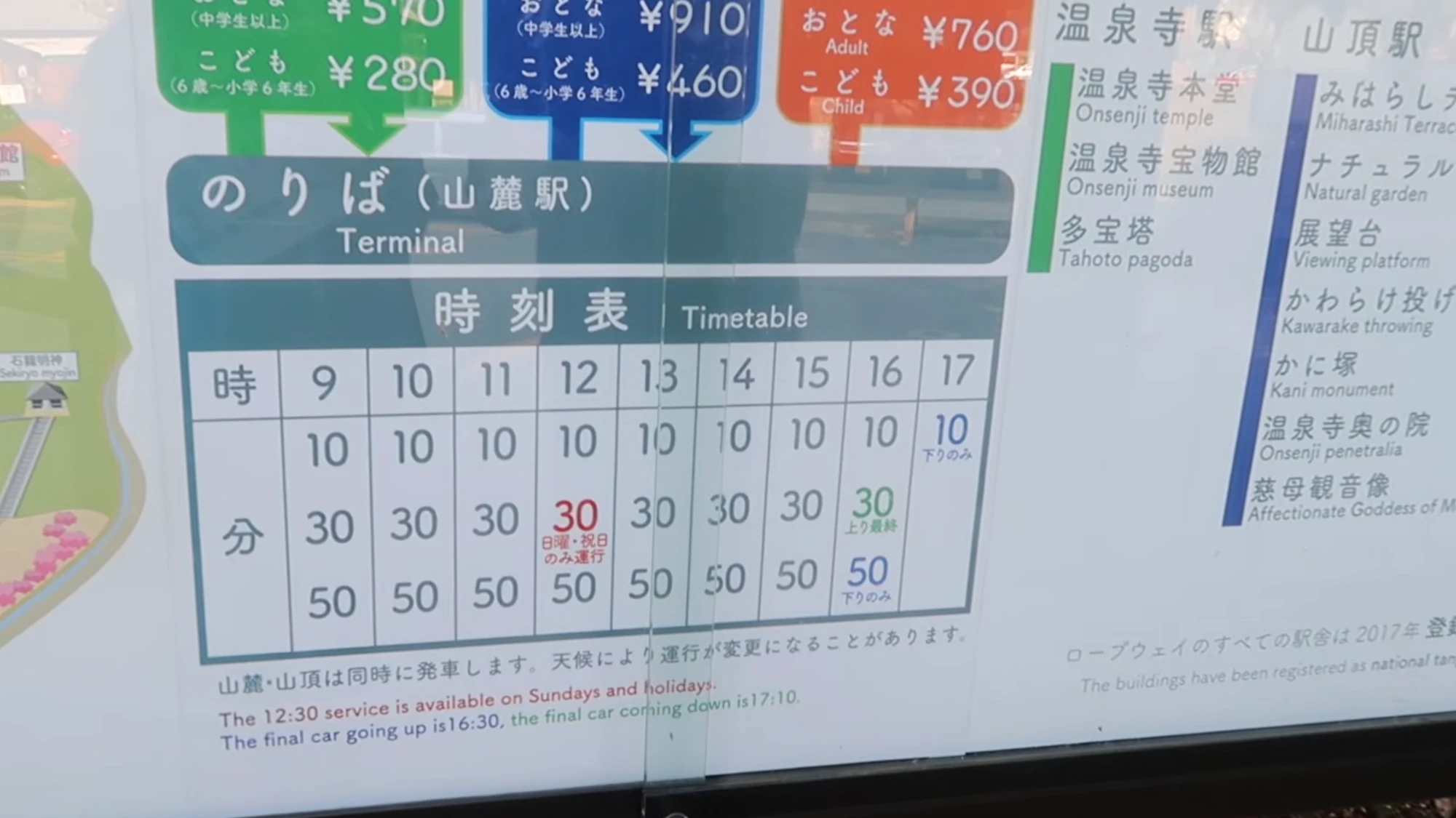 Bilingual fare and timetable board for the Kinosaki ropeway showing Onsenji and summit prices.