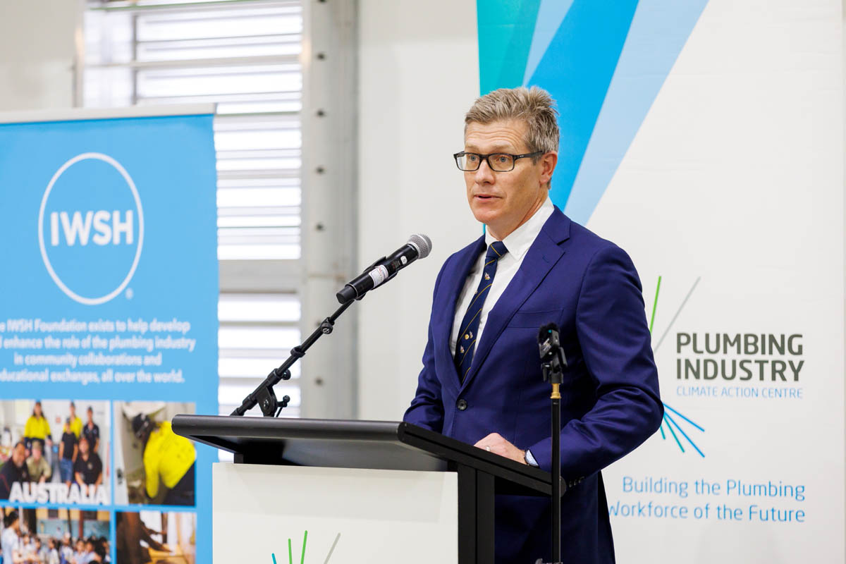 Man speaking at podium at formal event with blue lighting