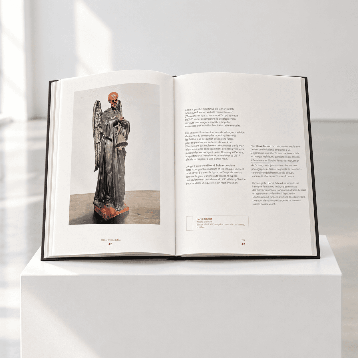 Catalogue XXH de la Fondation Francès ouvert aux pages 42-43, présentant l'œuvre l'Ange à la cloche d'Hervé Bohnert, une sculpture en bois du XIXᵉ siècle transformée en ange à tête de squelette tenant une cloche, accompagnée d'un texte de présentation.