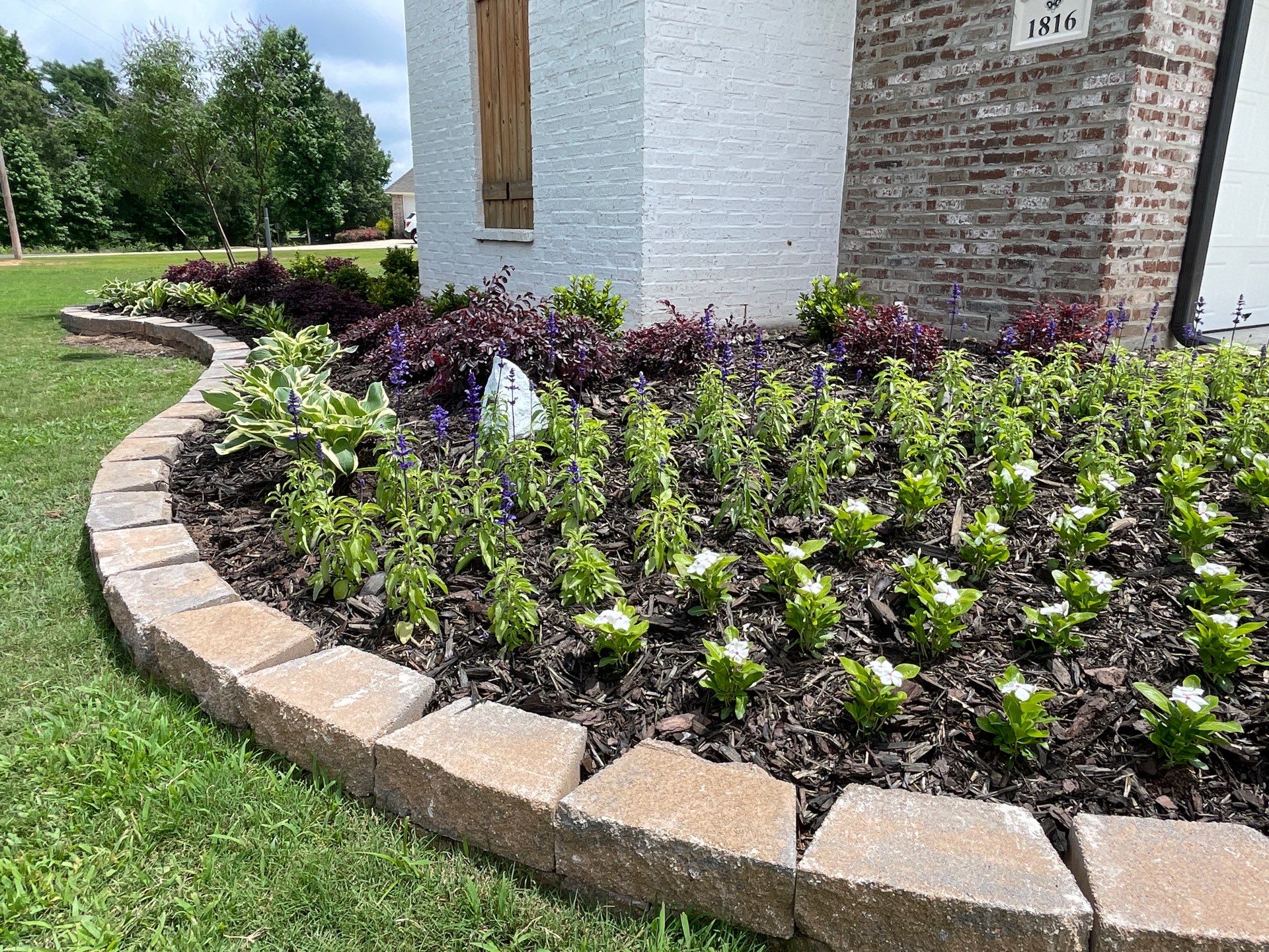 Professional lawn care and landscaping with trimmed grass and neat flower bed at a Shreveport home.