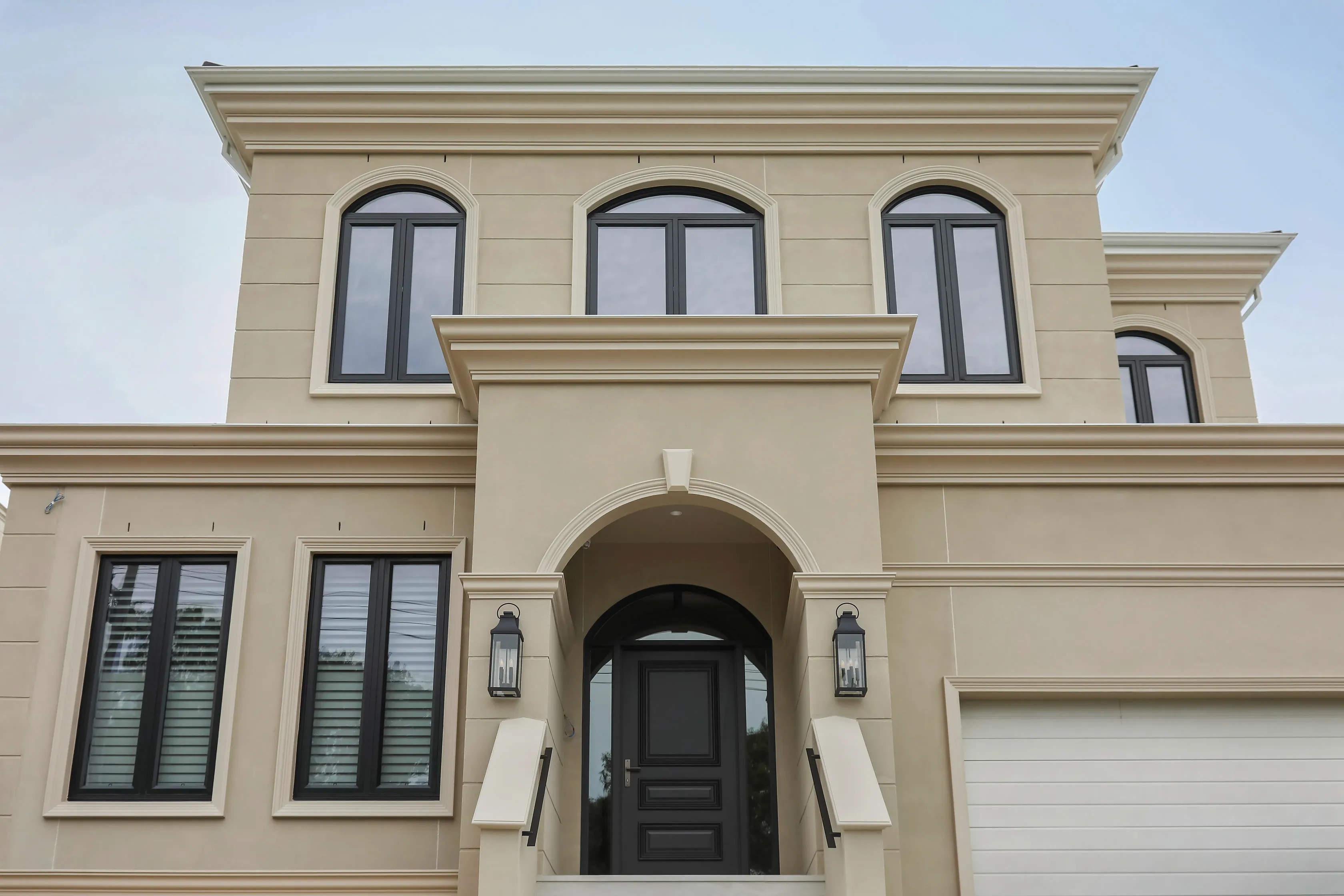 Templestowe Residence facade, a rendered two-storey home with arched windows and an arched entry portico over a black front door