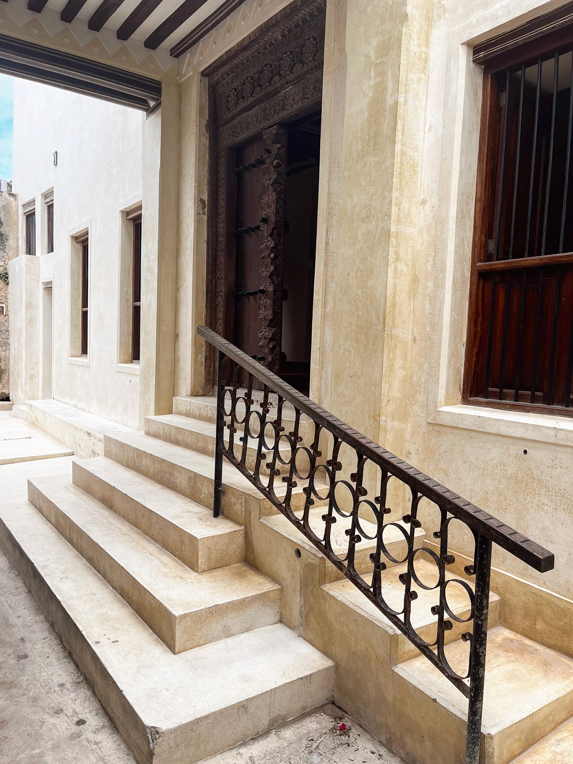A straight terrace view featuring a distant doorway framed by multiple cream-colored pillars.