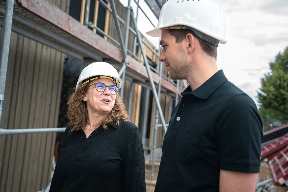 Mitarbeitende von Fries Architekten tauschen sich auf einer Baustelle über den Fortschritt eines Bauprojekts aus.