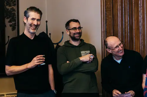 People standing and talking indoors with small objects.