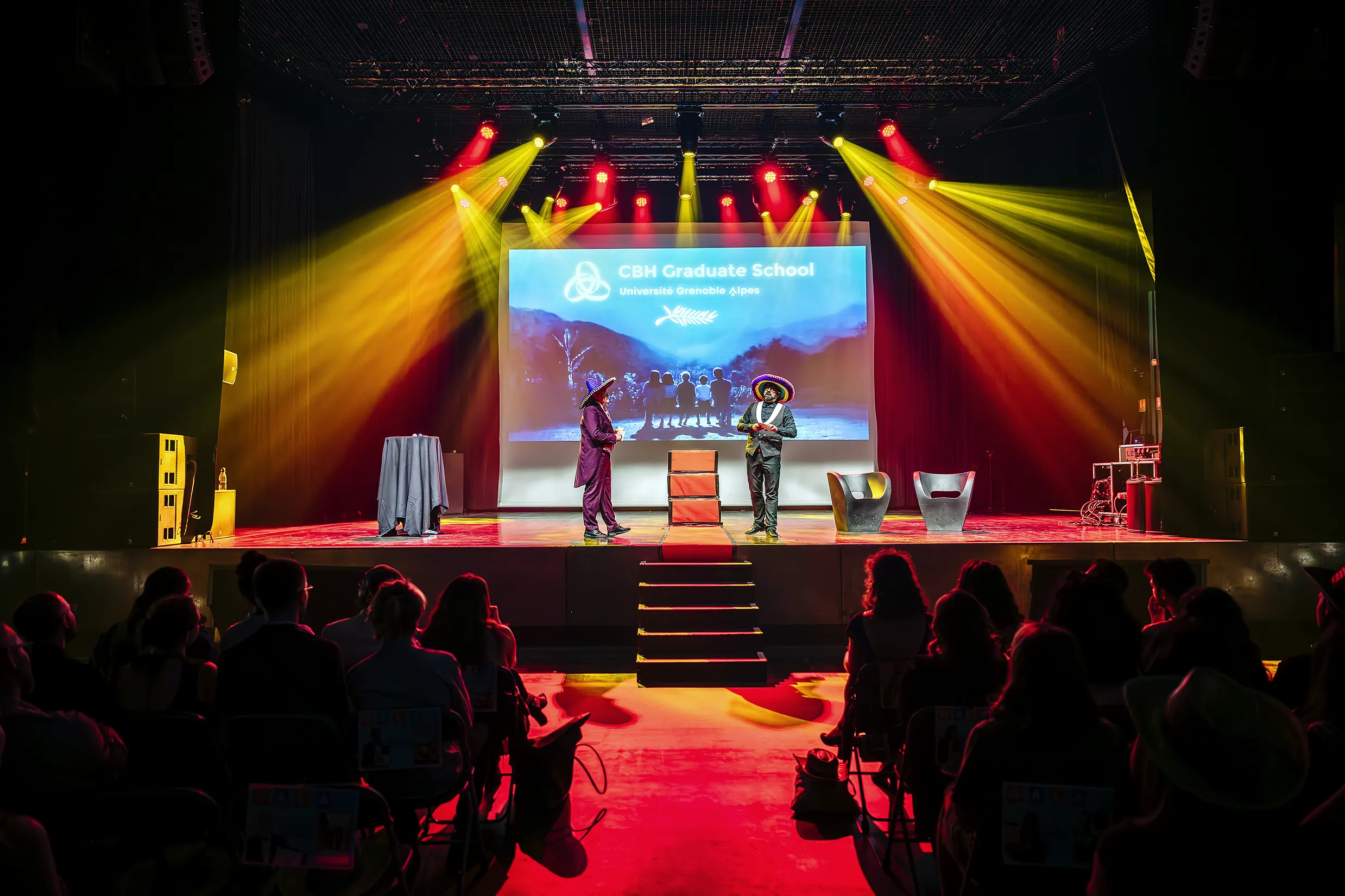 Performance scénique colorée avec éclairages rouges et jaunes au gala CBH Graduate School UGA