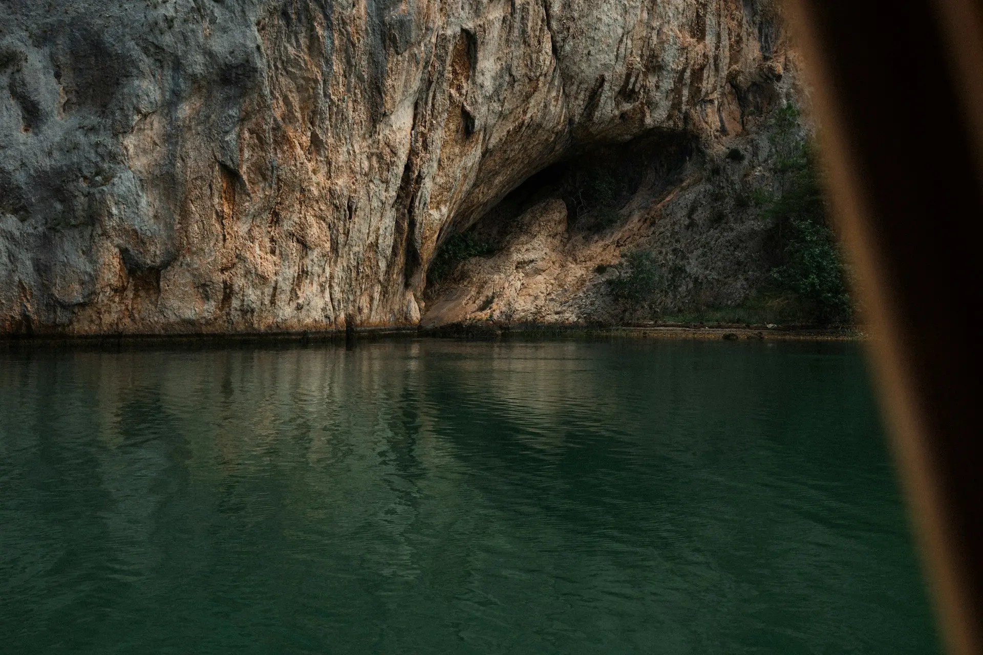 Cave entrance on a rocky cliff face above water.