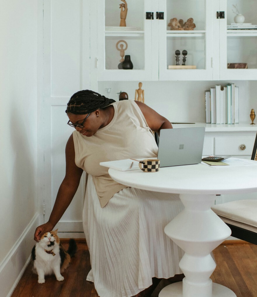  Woman sitting at table with cat, both looking content.