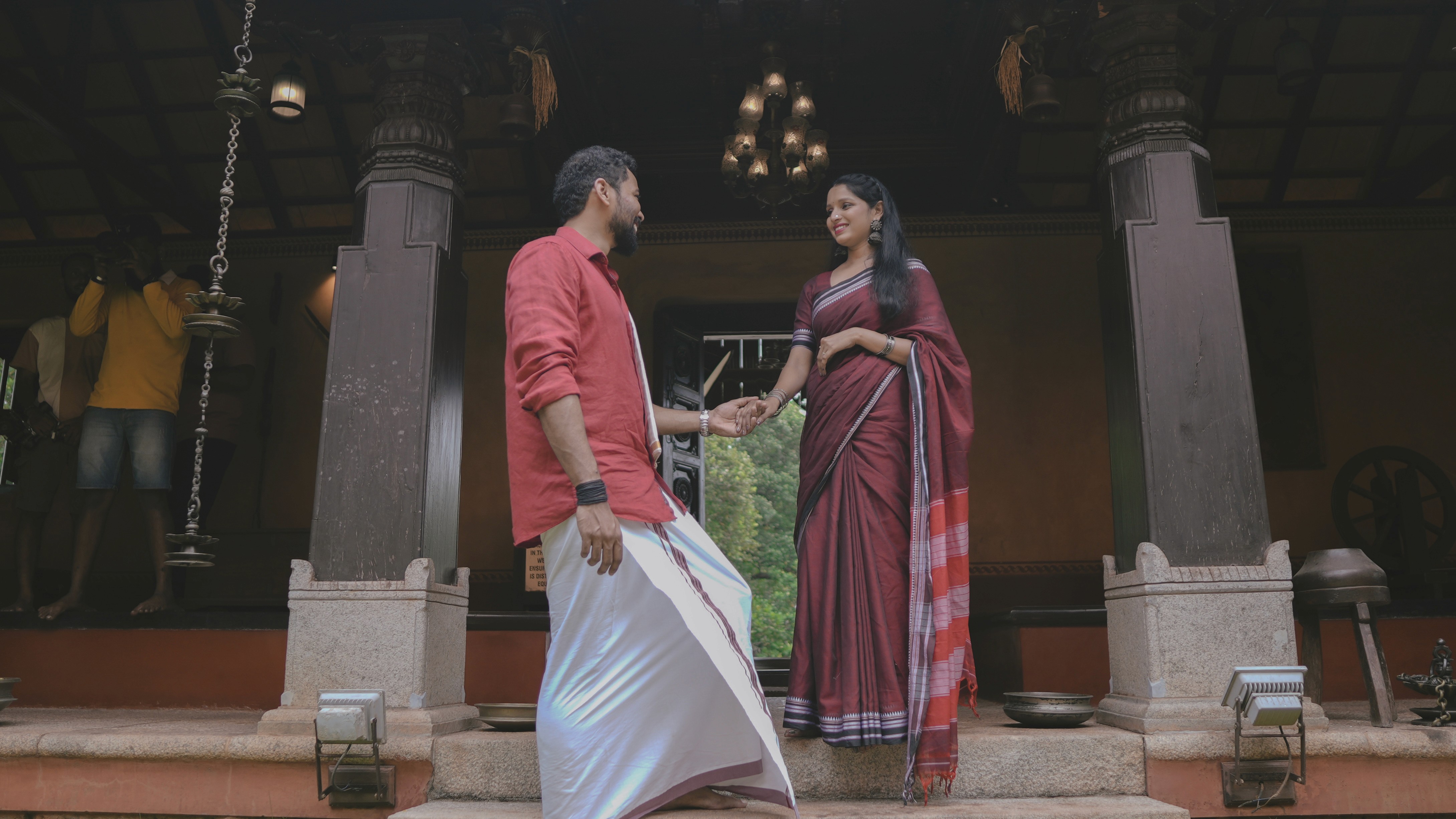 A Couple holding hands in traditional attire in an old-age traditional home