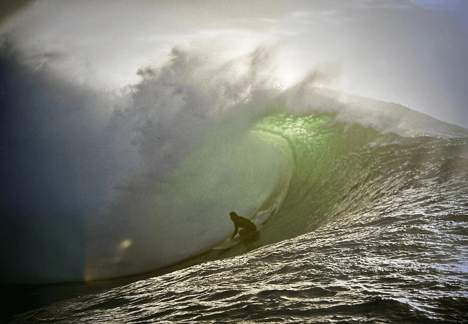 Surfer in a barrel wave as the sun sets