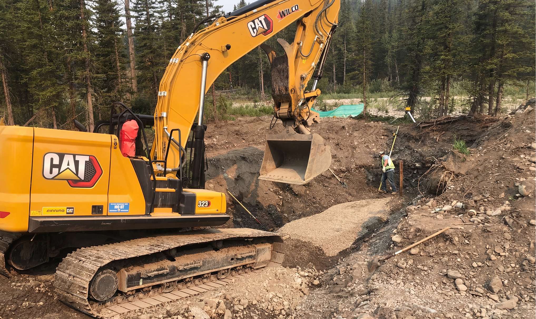 Wilco excavator with erosion control measures during flow gauge station construction on Elbow River in Bragg Creek