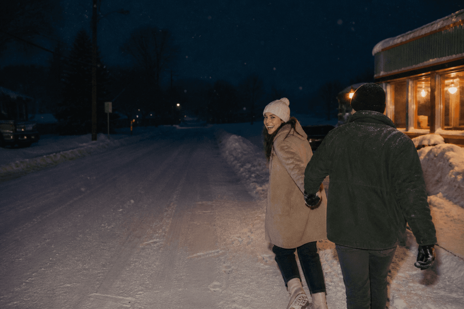 Couple leaving a warmly lit diner on a snowy night