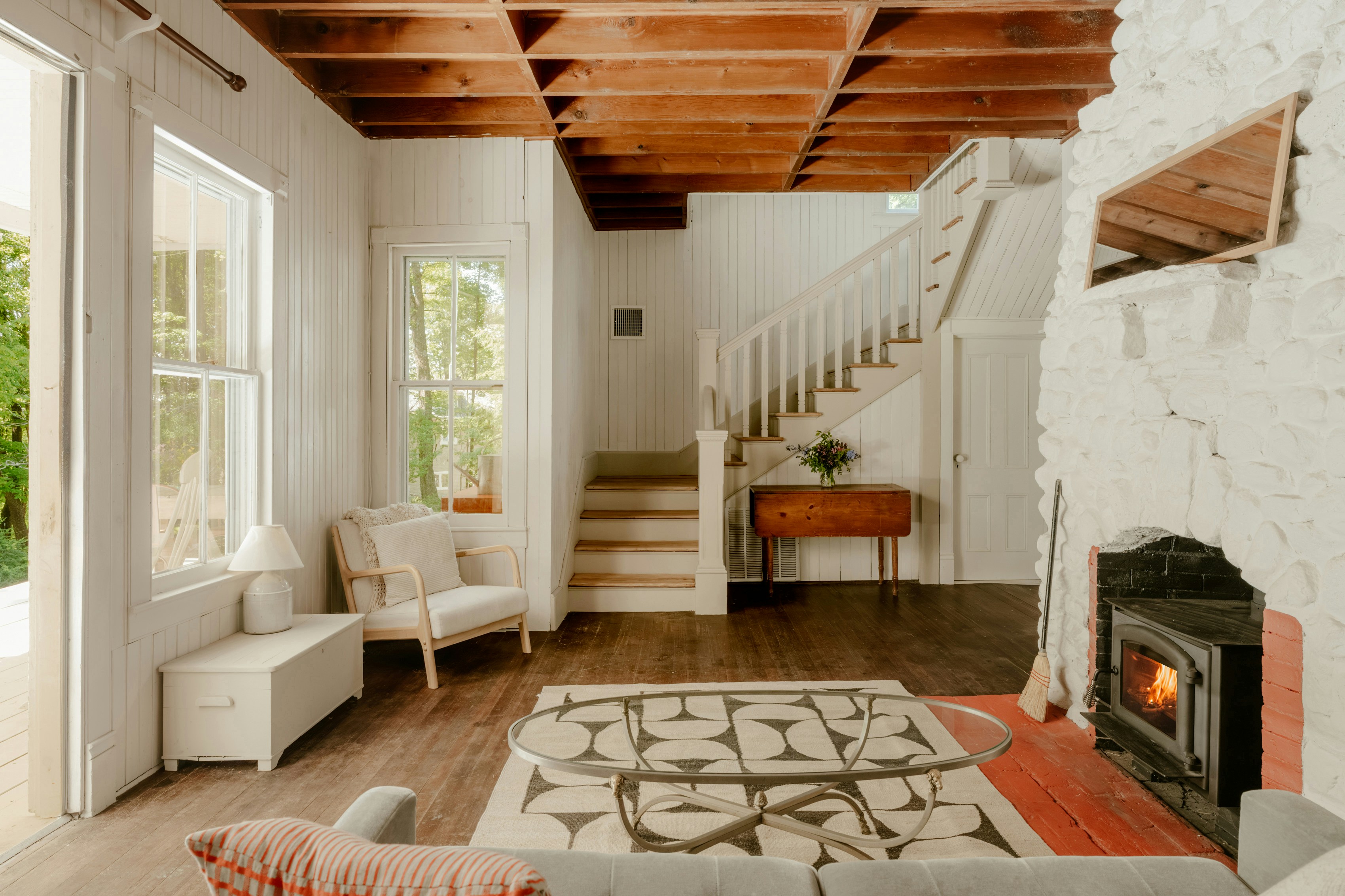 Bright living room with fireplace, wood ceiling, staircase