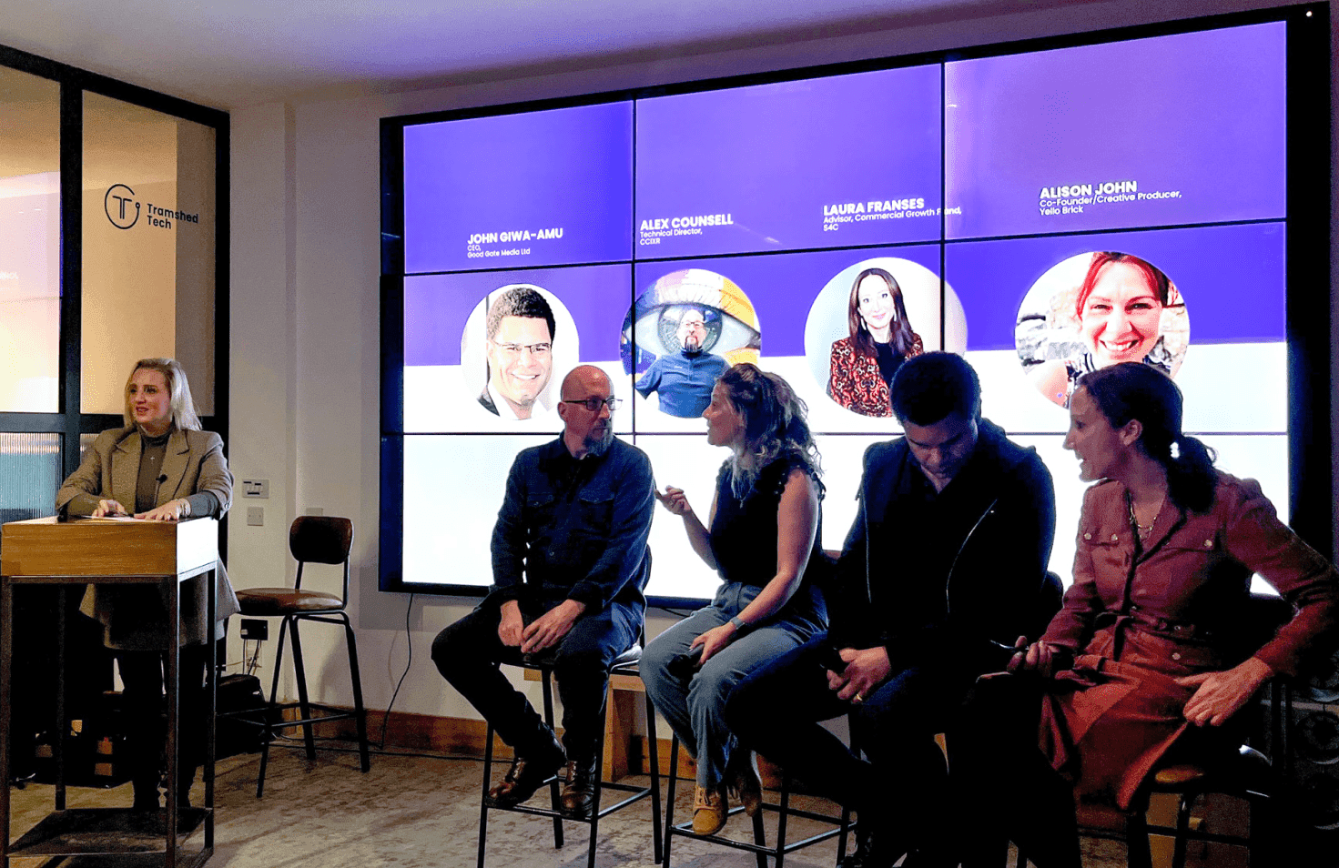 People talking in front of a large screen.