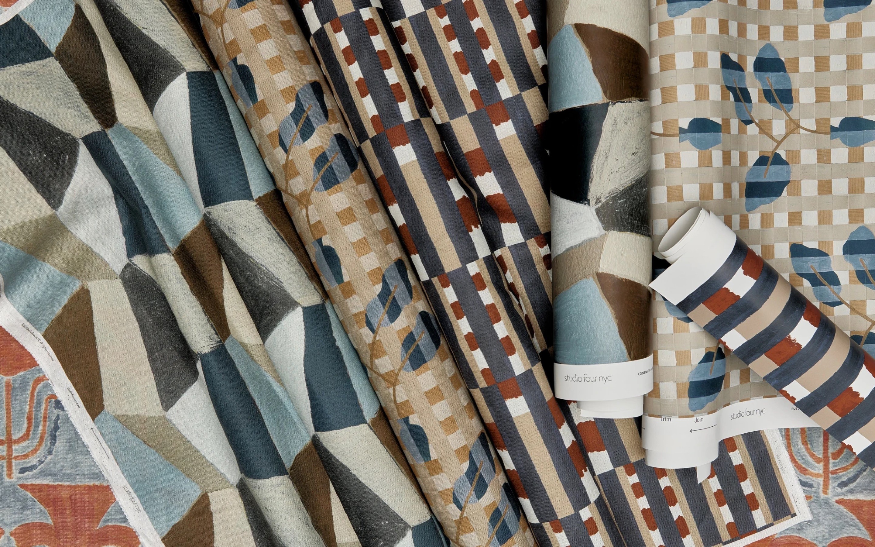 Various rolls and swatches of printed wallpaper and textiles.