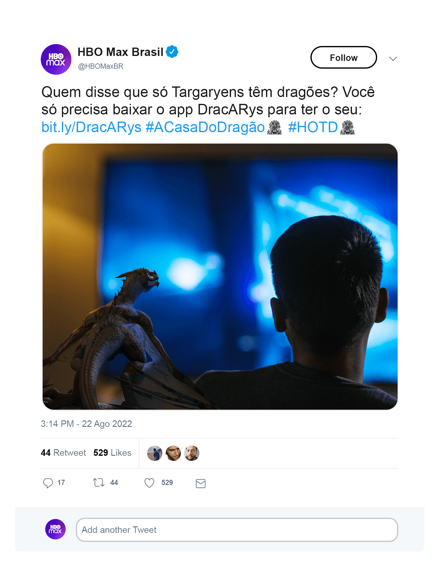 Man sitting on a couch watching TV with a baby dragon beside him in a social media promotion.