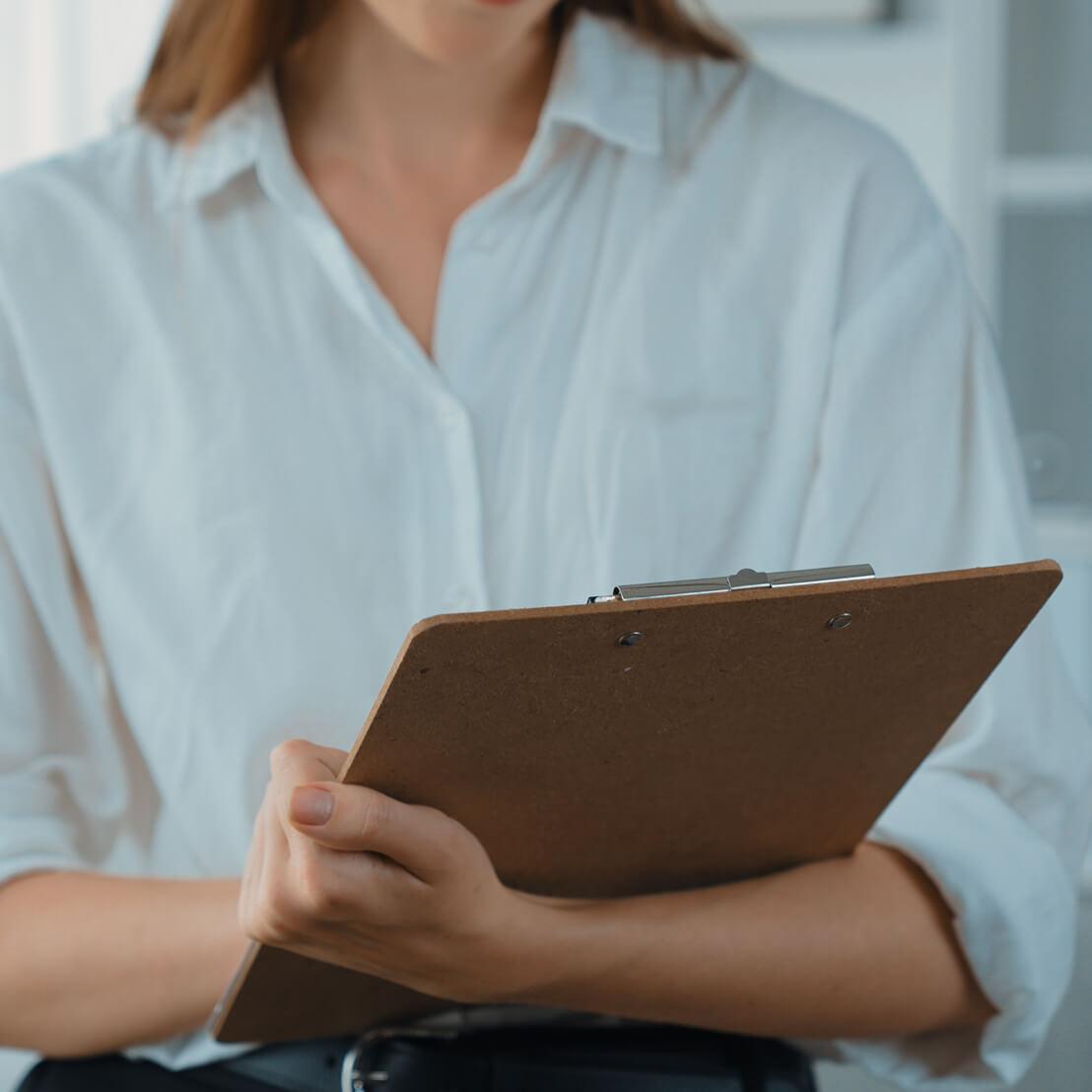 Therapist holding a clipboard while taking notes during a session
