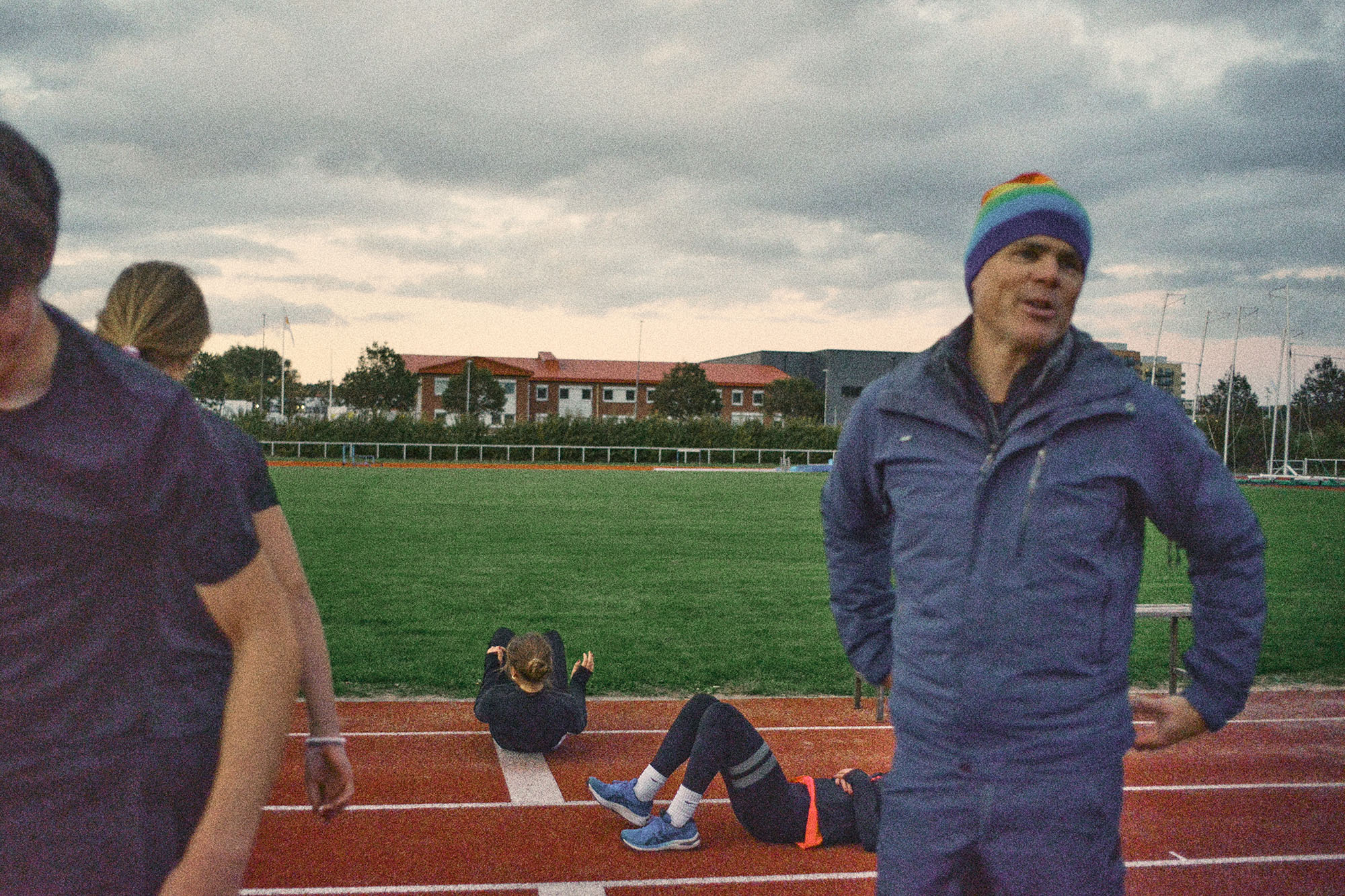 Bild på flera personer som värmer upp för en träning där en ledare står med en mössa.