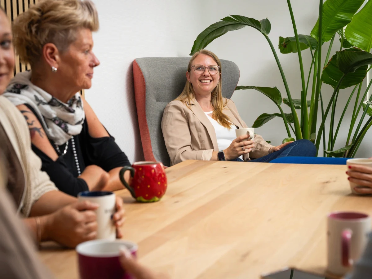 Mitarbeiterinnen einer Steuerkanzlei im entspannten Austausch bei Kaffee am Besprechungstisch