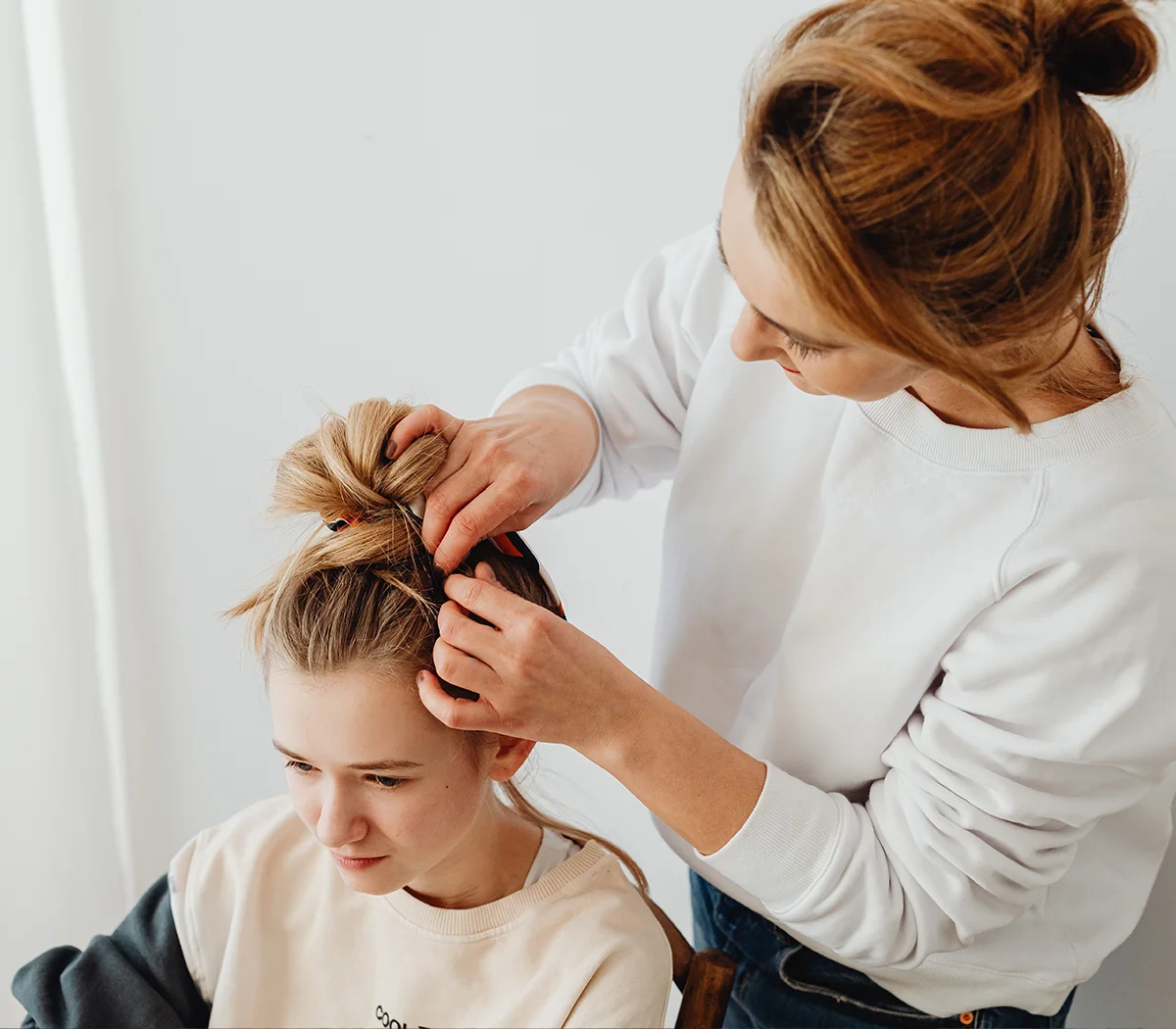 A teenage girl getting her hair put in a bun for head lice treatment