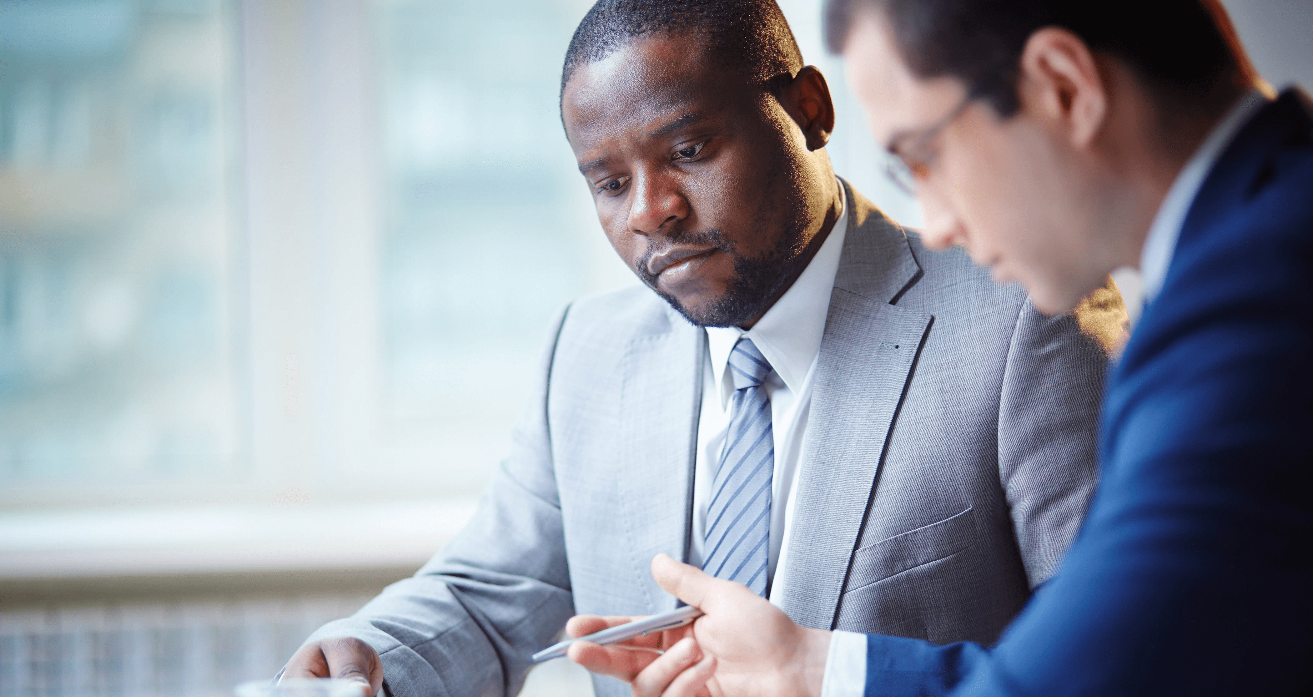 Auditor überprüft Dokumentation zu Datenschutzrisiken mit einem Prozessverantwortlichen in einem fokussierten Auditsetting, das die Prüfung des Datenschutzrisikomanagements, der gesetzmäßigen Entscheidungsgrundlagen und der Kontrollenwirksamkeit gemäß ISO/IEC 27701 darstellt.