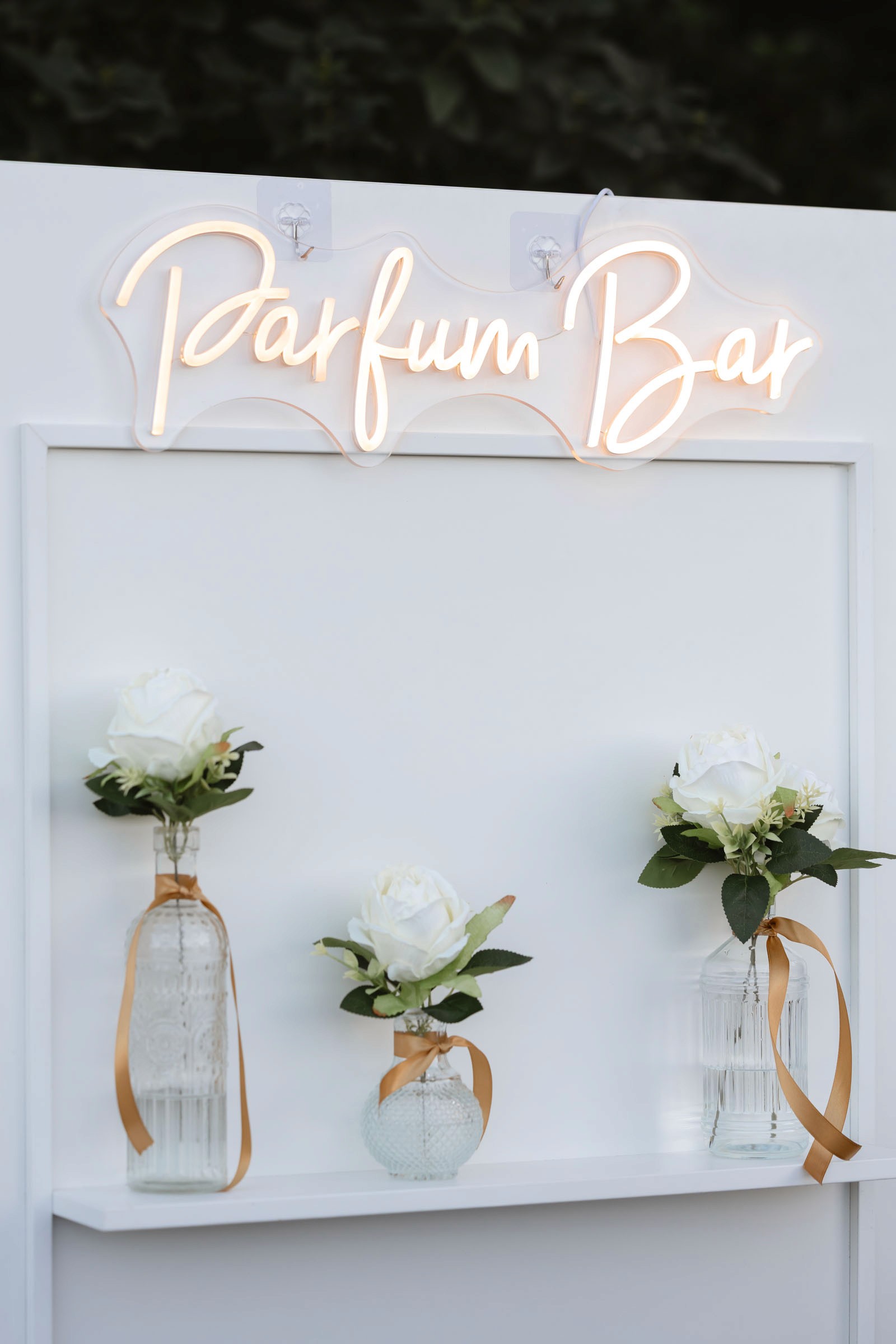 White floral arrangements displayed beneath a glowing Parfum Bar sign at the castle reception.