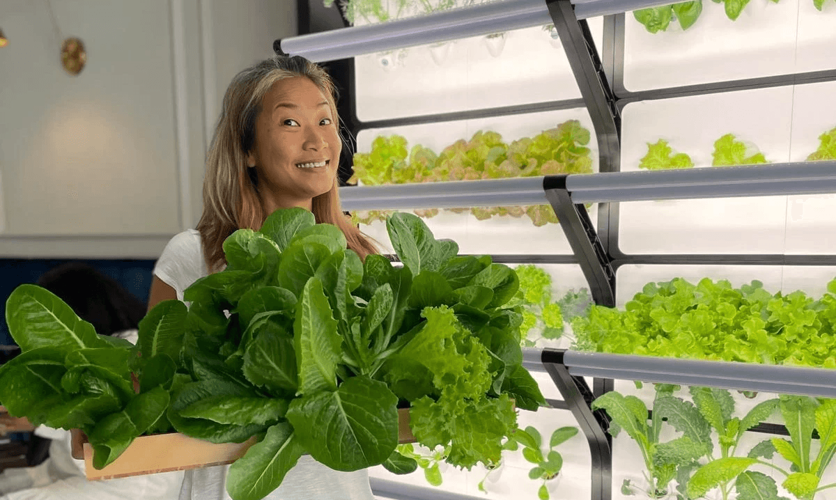 A woman posing with fresh greens harvested from a Grobrix wall
