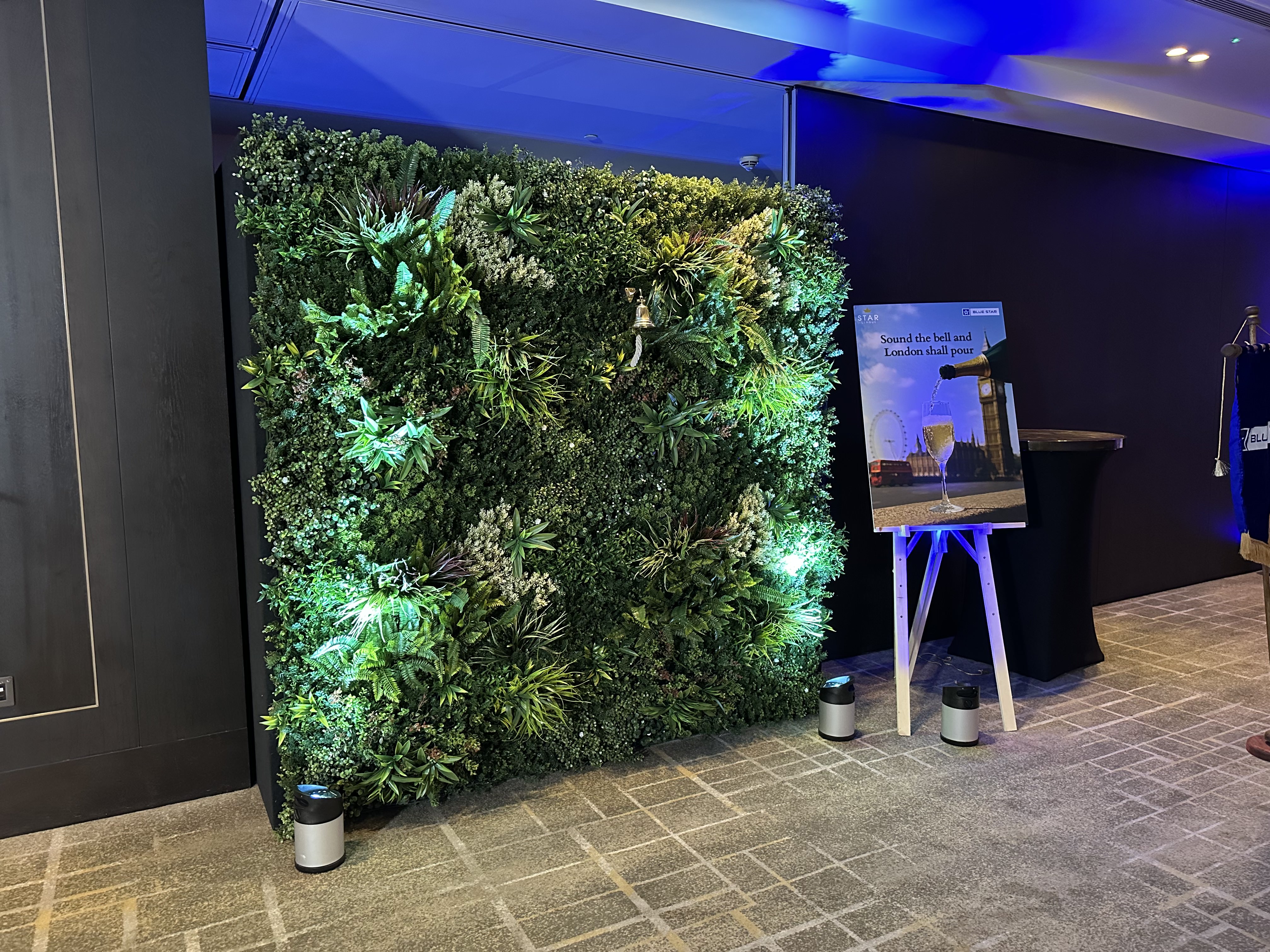 Illuminated foliage wall with a guest bell and champagne activation at the Bluestar Knights of Honour Awards 2025 in London.