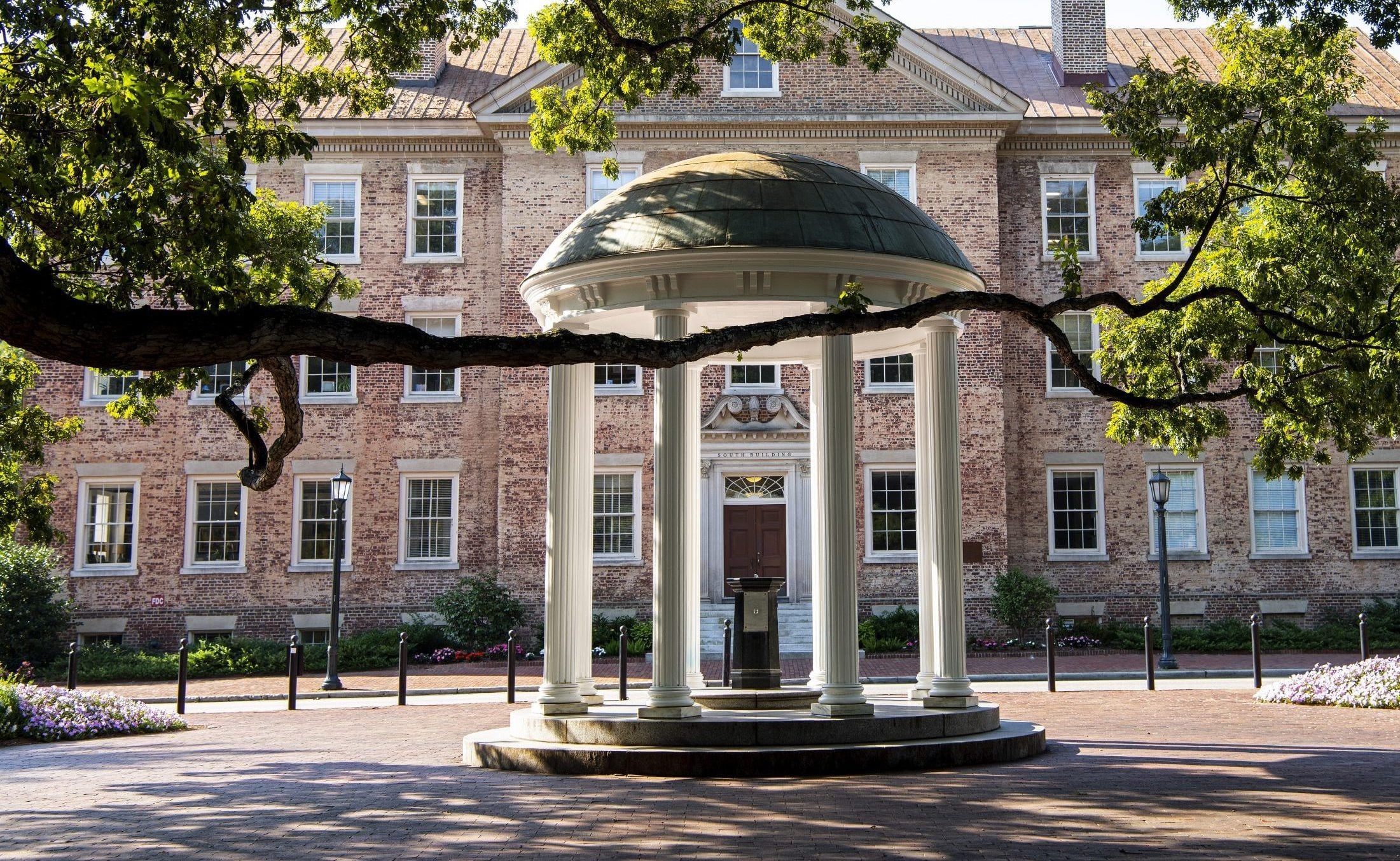 The Old Well framed by tree branches in front of South Building at UNC Chapel Hill