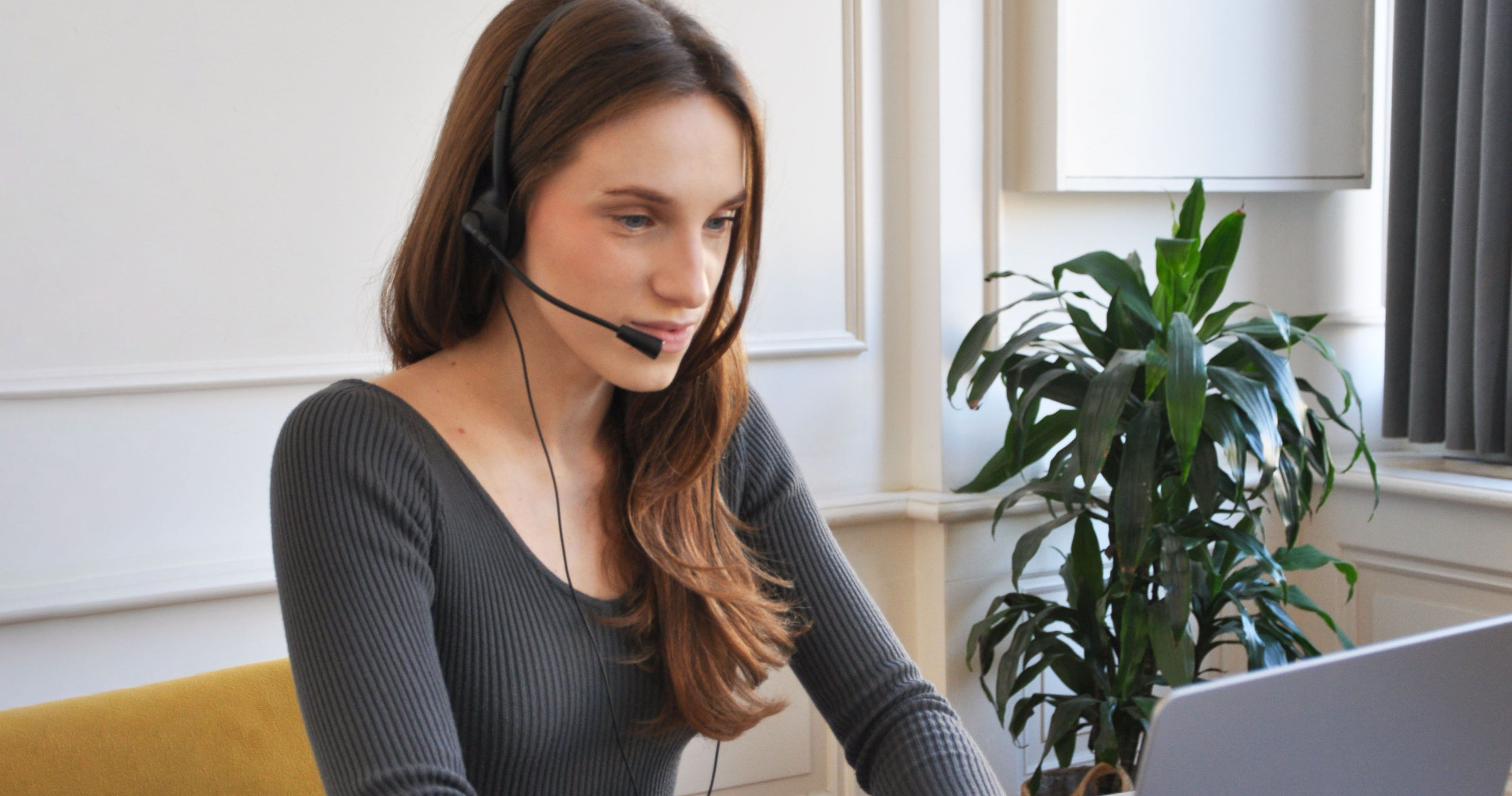 Yuliia Lukianenko, Helpline Operator at Empatia, talking to a caller while wearing a headset in the office