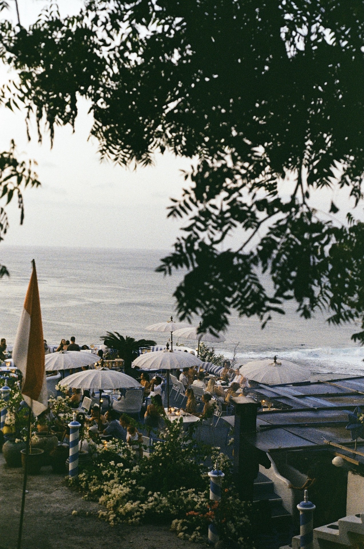 Film Photography of people watching the sunset as surfers ride the waves in Uluwatu, Bali