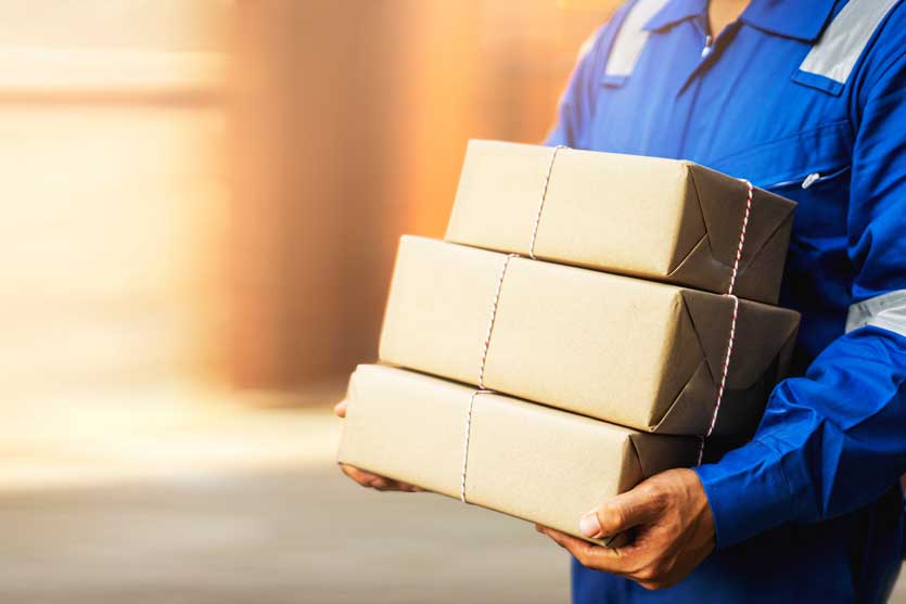 Mail worker carrying a stack of packages.