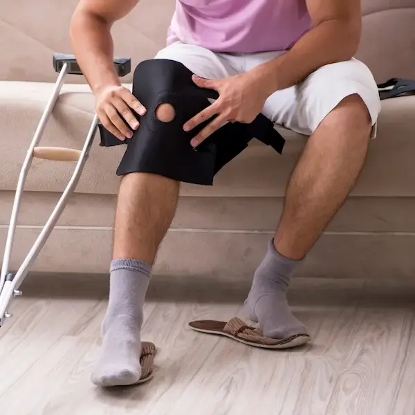 Injuried male persons legs putting on knee brace