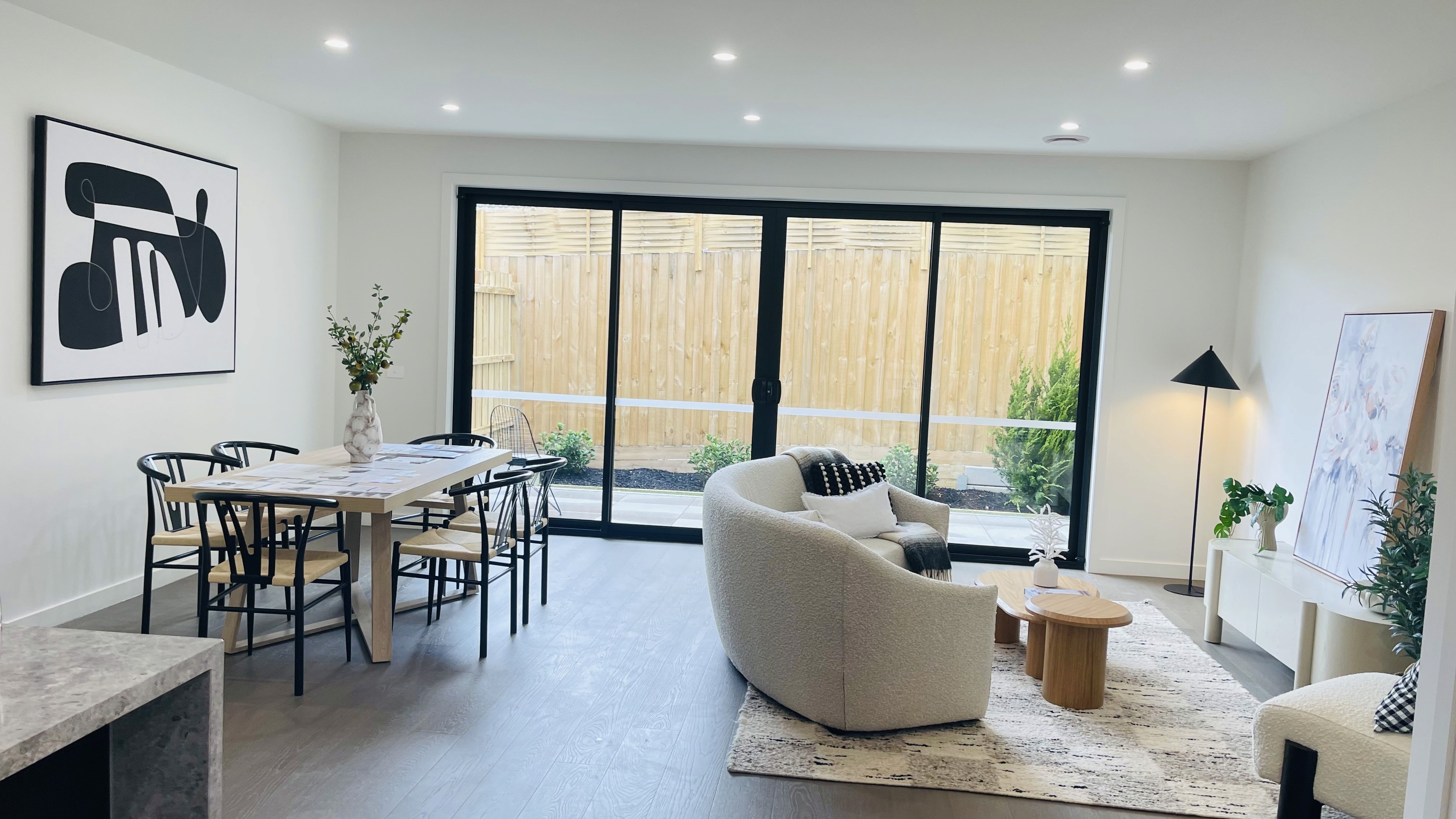 Spacious, luxurious living room with high ceilings, an elegant beige sectional sofa, warm ambient lighting, classical artwork, and rustic architectural elements, featuring an open layout with a view of a mezzanine level.