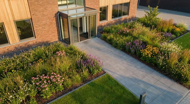 Verzorgde entree van een bedrijfspand met kleurrijke bloemen en netjes onderhouden planten.