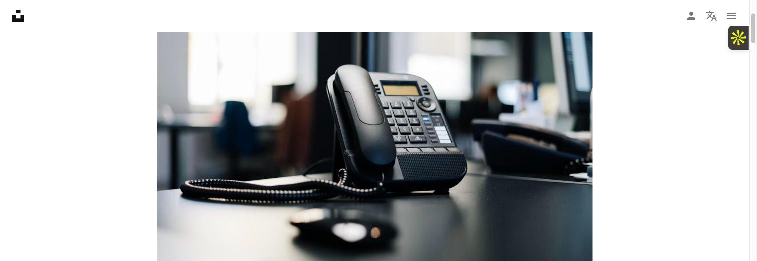 Office desk phone sitting unanswered on a desk in an empty office