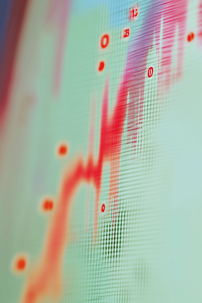 A young woman with curly hair and glasses smiles warmly while sitting in a sunlit room filled with various potted plants, creating a cozy and inviting atmosphere.