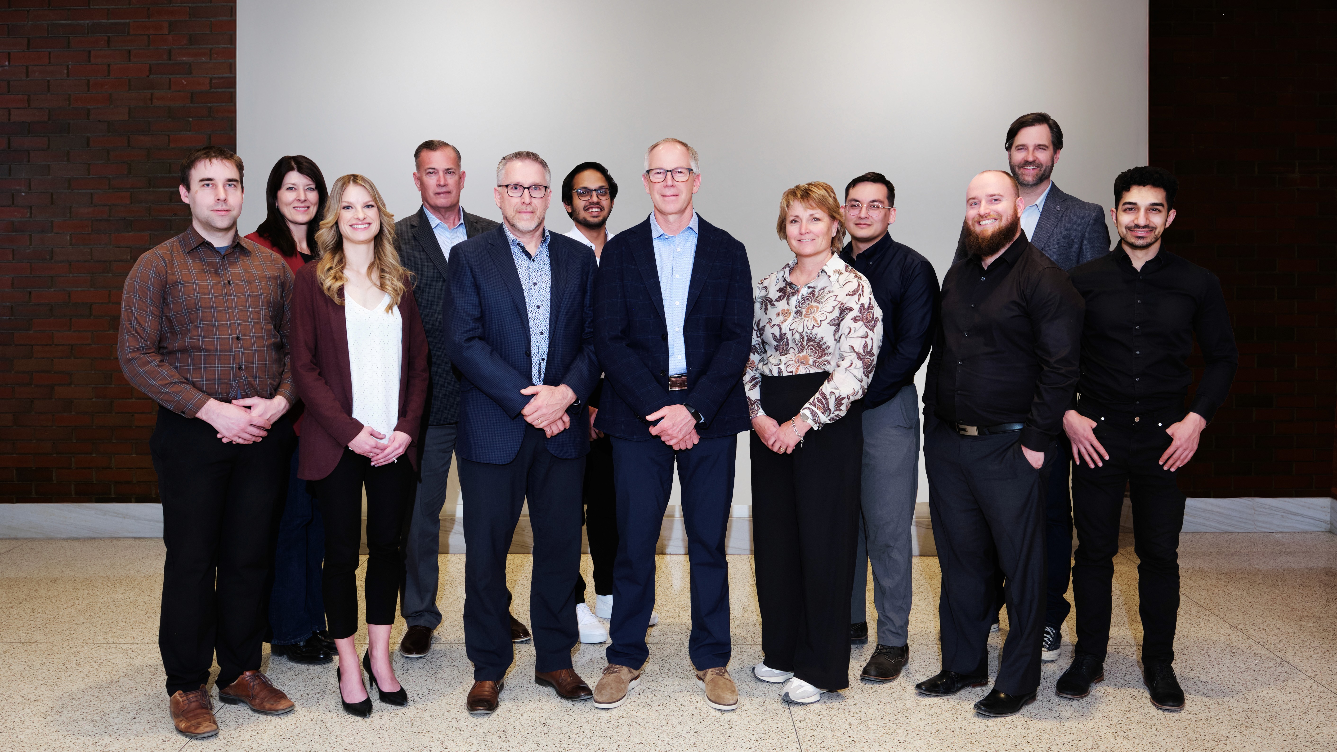 A large group photo of diverse team members gathered in an industrial-style space with arched ceiling.